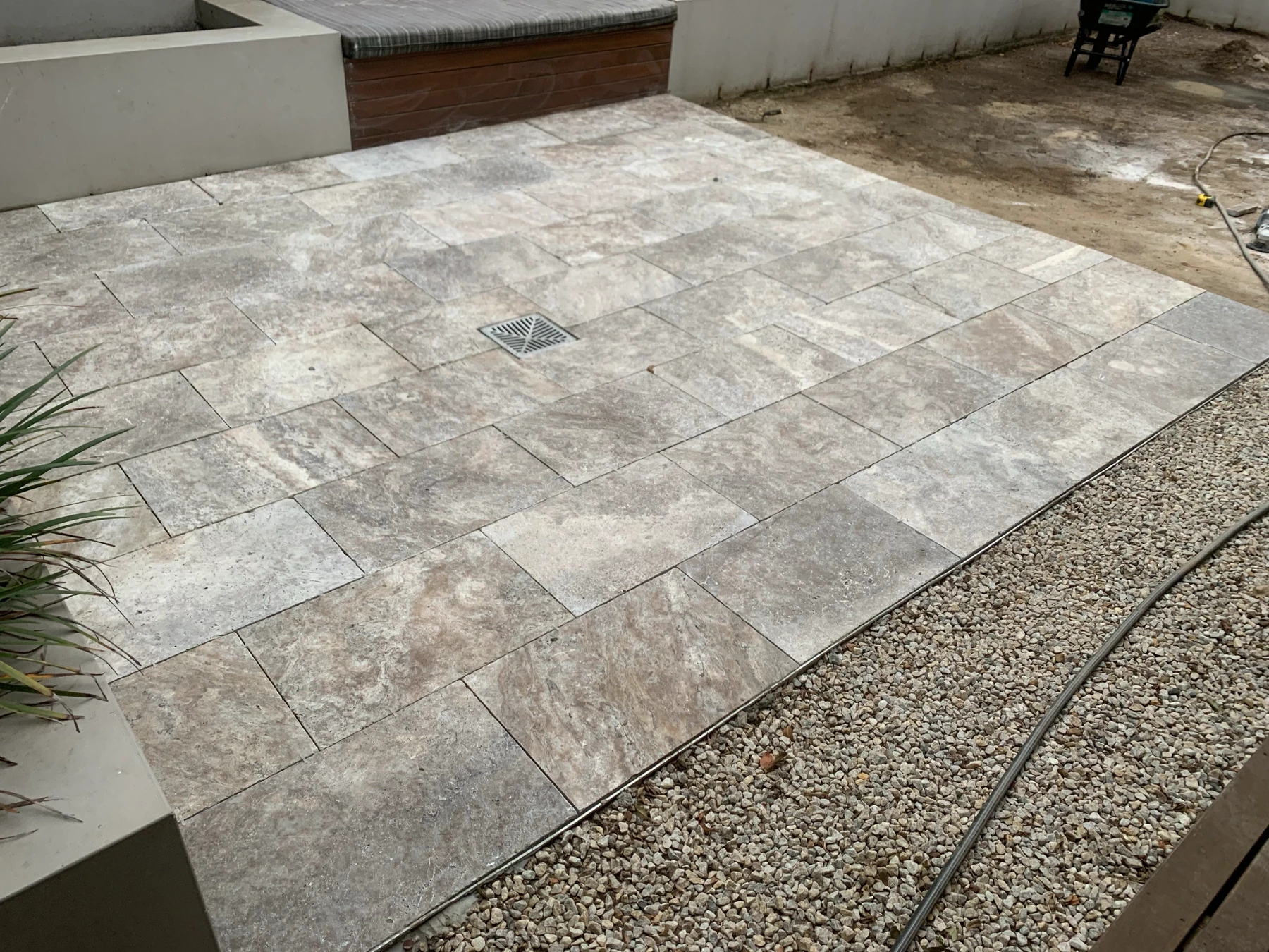 Stone courtyard paving with a gravel border and built-in seating, with surrounding work in progress