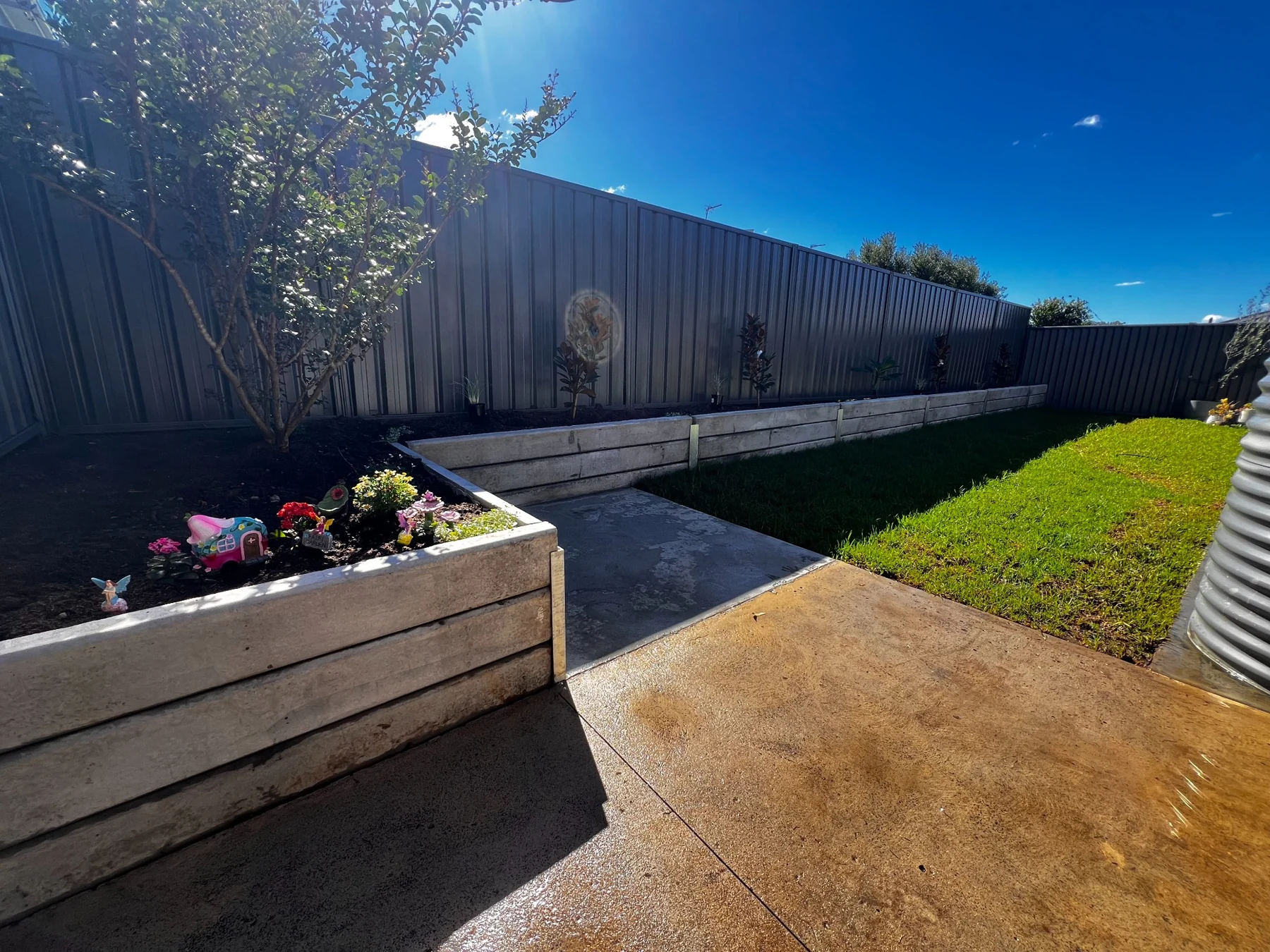 Raised sleeper garden beds around a green backyard