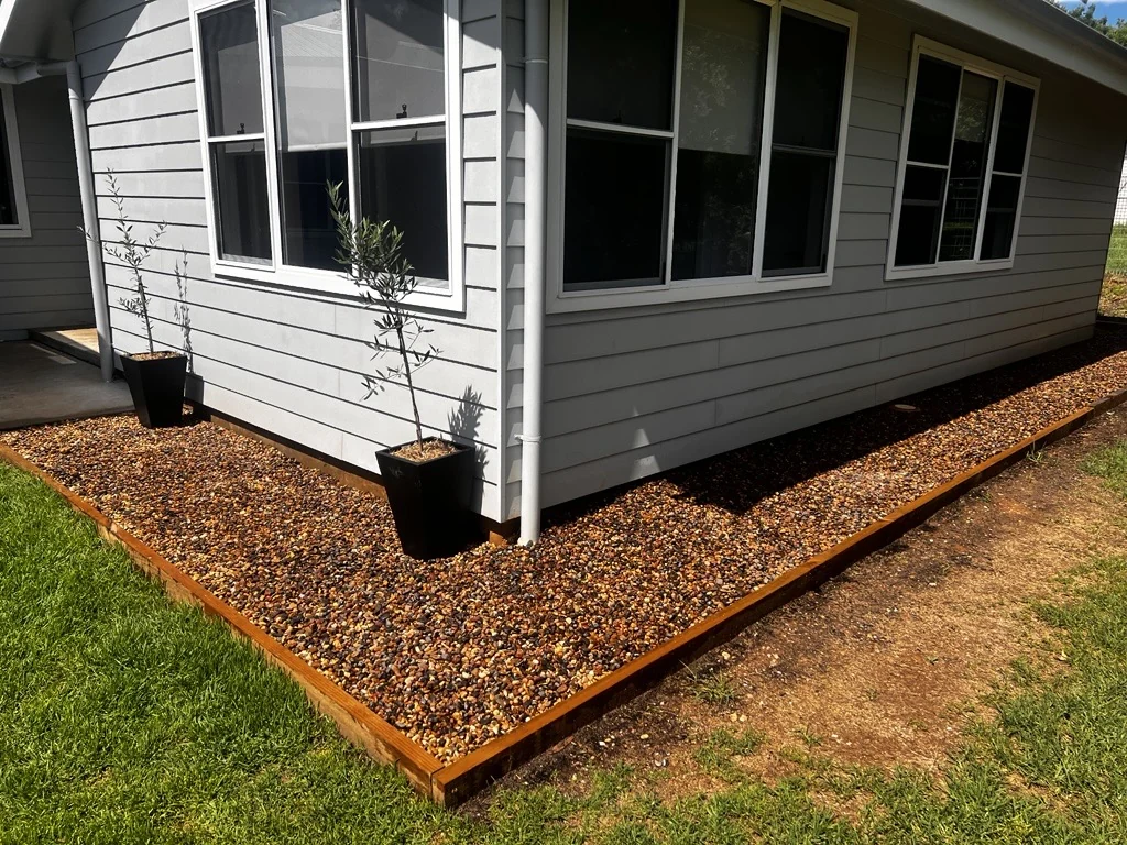 Steel edging defining a pebble border beside a house