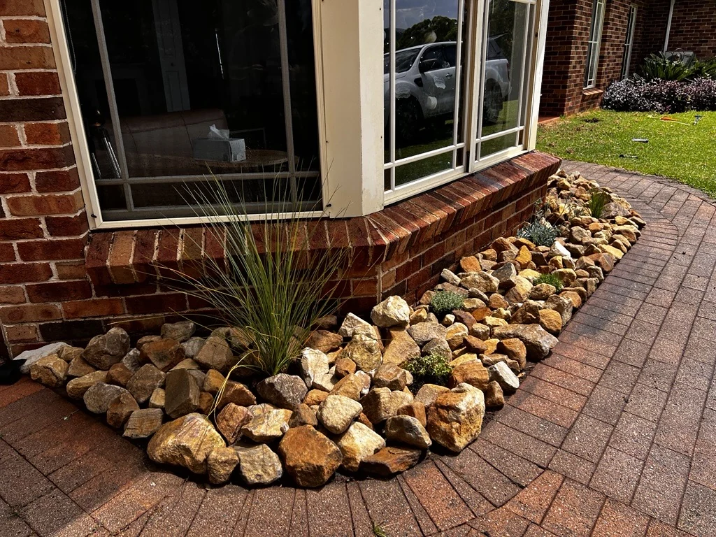 Stone garden border around a brick bay window