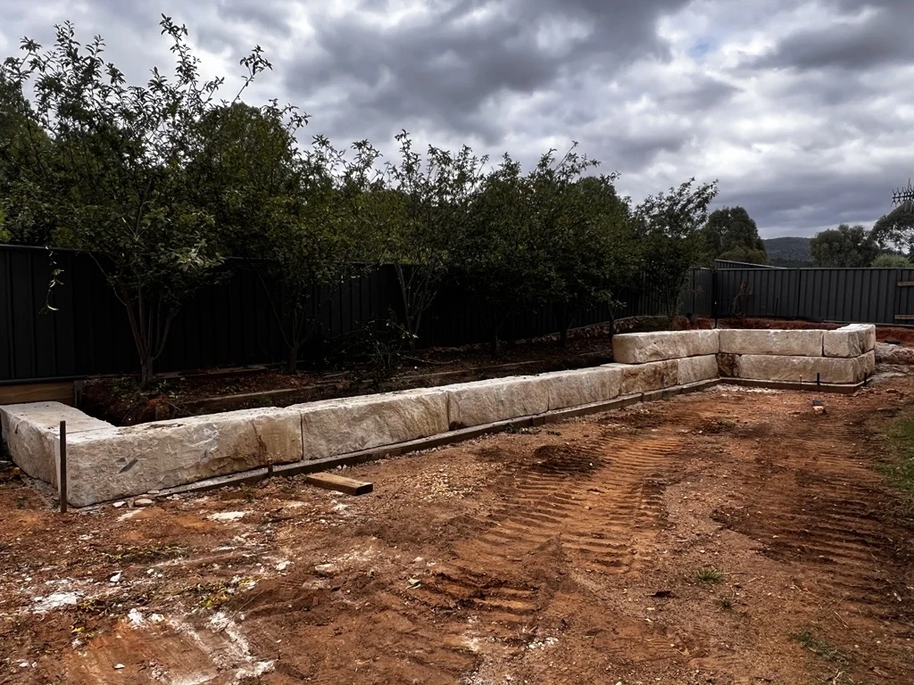 Sandstone retaining wall with prepared soil in the foreground