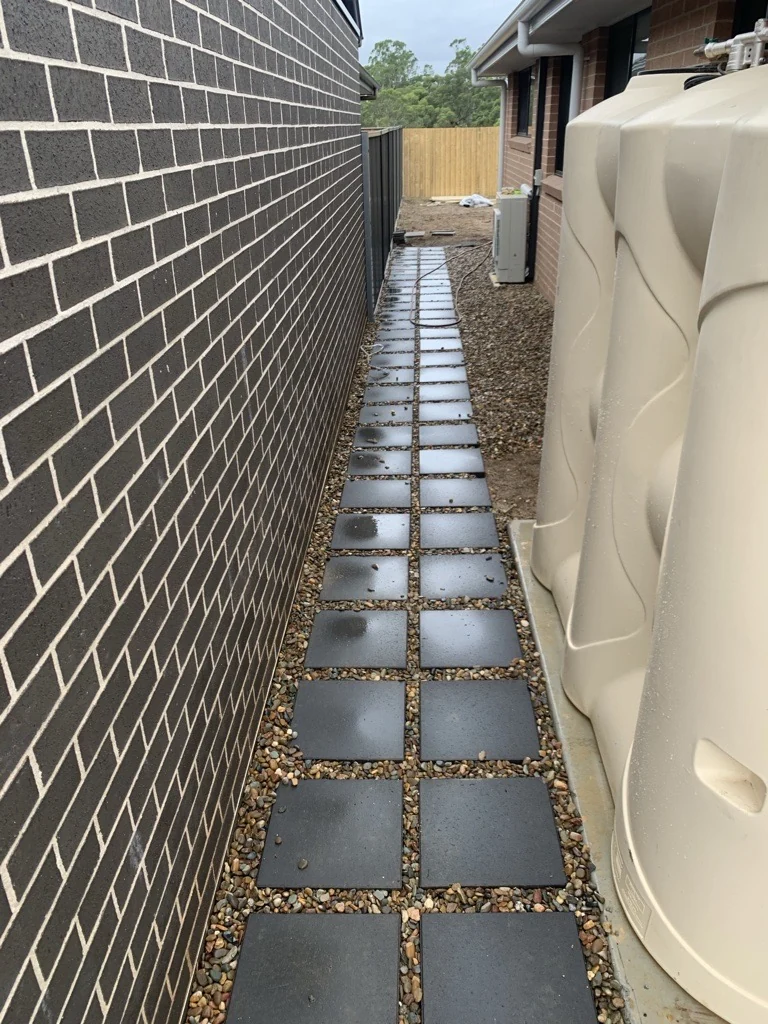 A straight paved side path beside a brick home